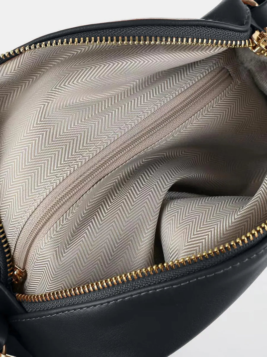 Black faux leather belt bag interior with chevron lining and gold zipper detail.