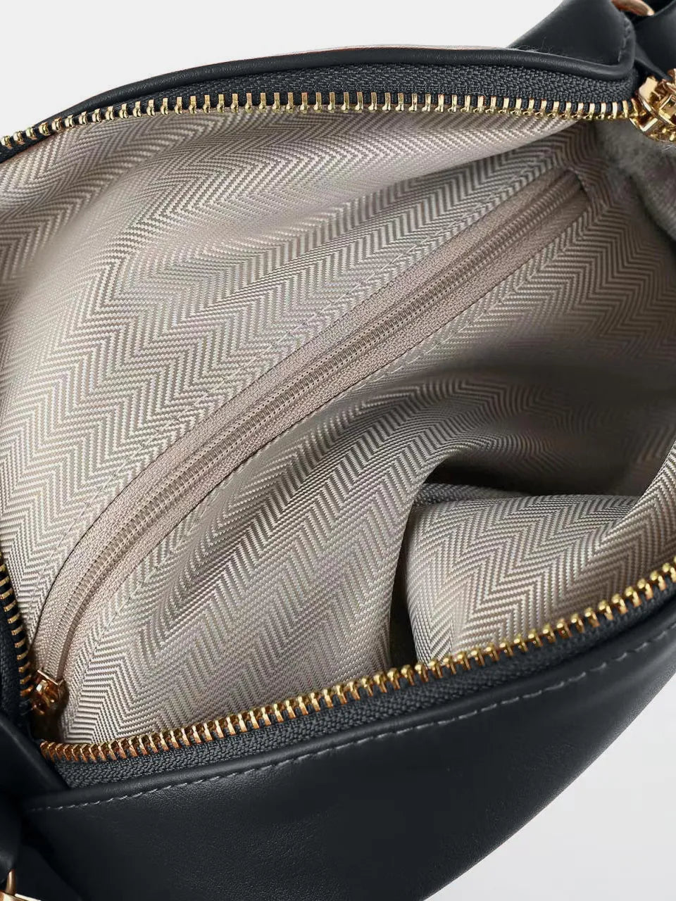 Black faux leather belt bag interior with chevron lining and gold zipper detail.
