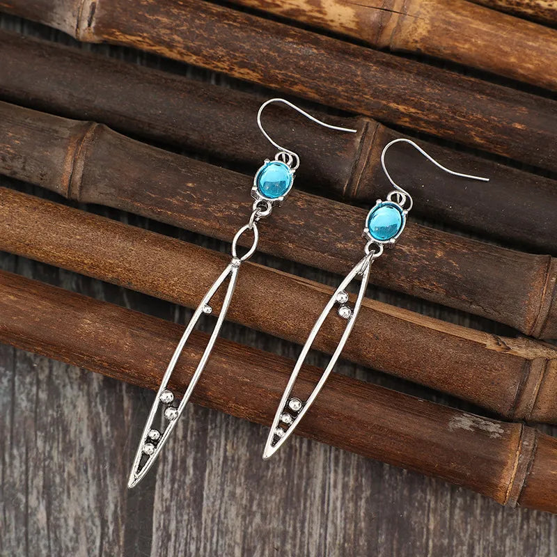 Silver dangle earrings with azure drop stones and elongated open frames with small bead accents.