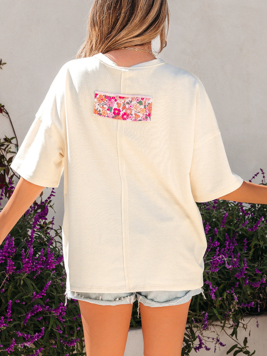 Cream cotton oversized t-shirt with floral chenille patch detail on back.