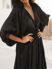 Black tie-neck midi dress with puff sleeves and a tiered skirt.