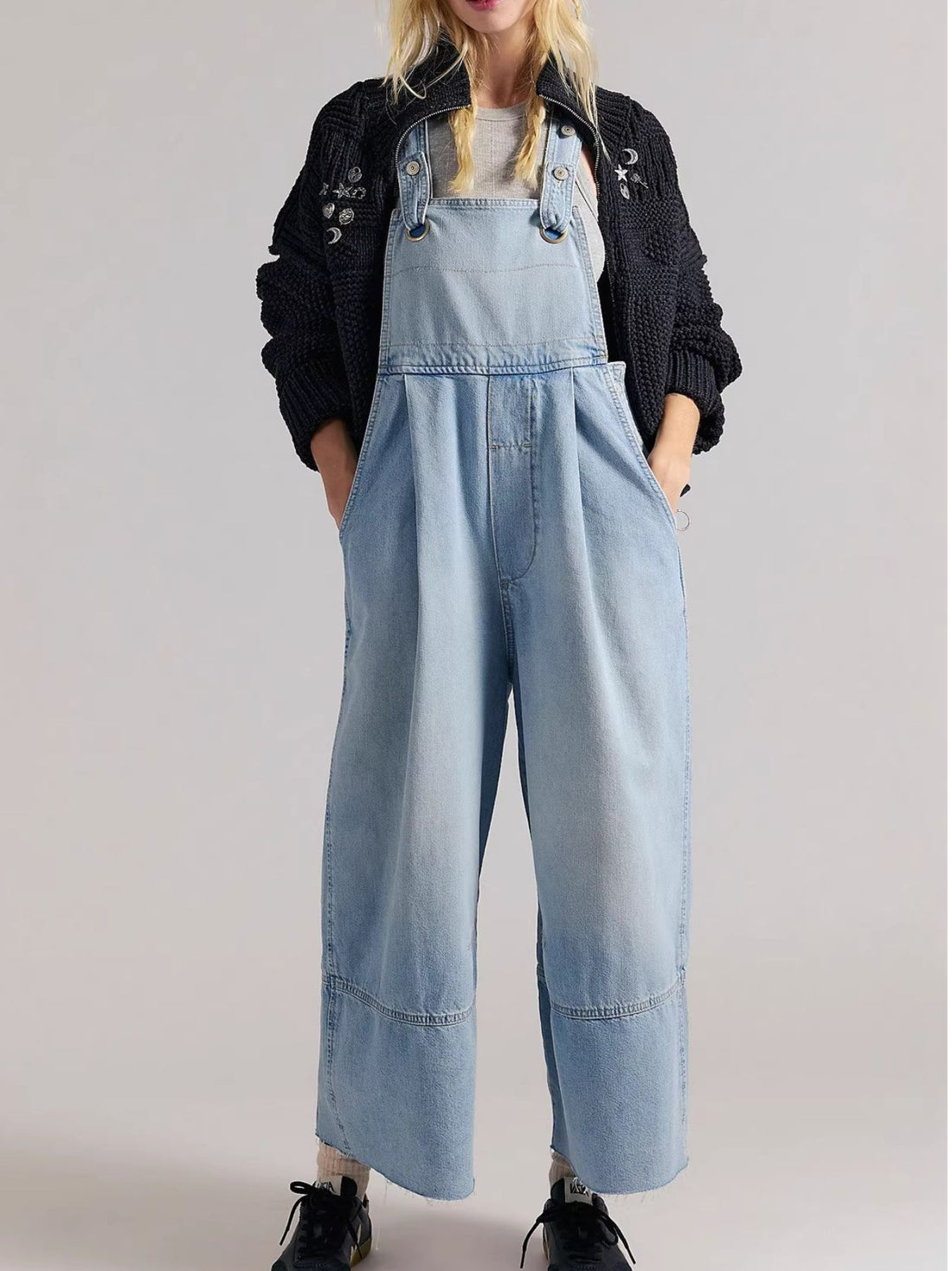 Light blue denim overalls with wide legs and raw hem, styled with a black cardigan.