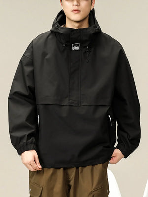 Black oversized hooded windbreaker jacket with drawstring hood and chest logo.
