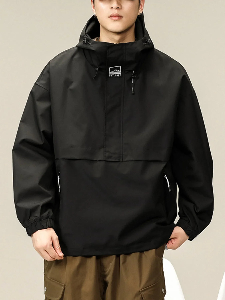Black oversized hooded windbreaker jacket with drawstring hood and chest logo.