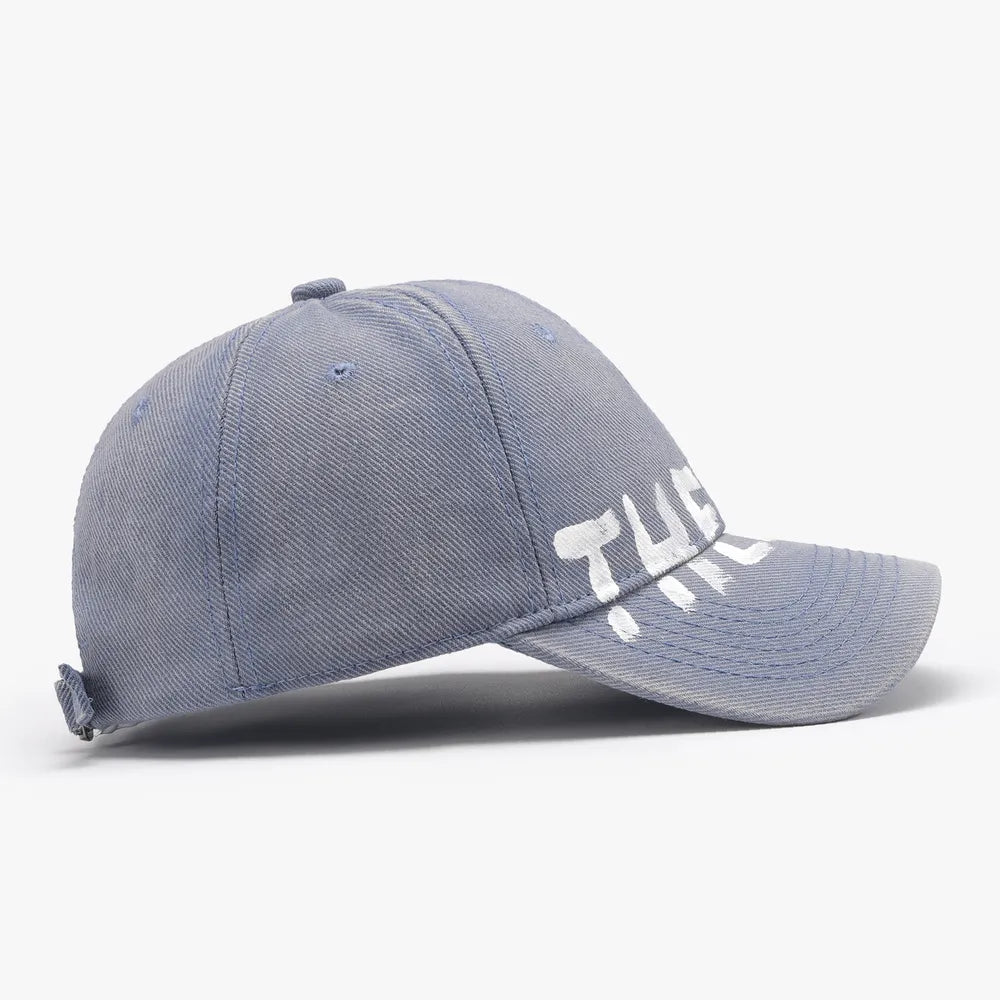 Dusty blue textured denim baseball cap with white graphic text.