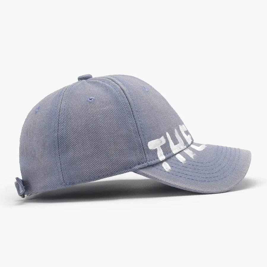 Dusty blue textured denim baseball cap with white graphic text.