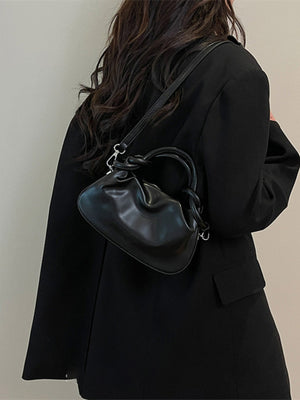 Black ruched crossbody bag with knot handle and adjustable strap.