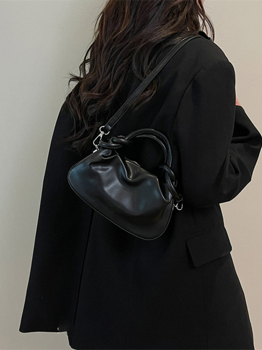 Black ruched crossbody bag with knot handle and adjustable strap.