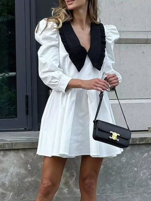 White puff sleeve mini dress with black ruffled collar and plunging neckline.