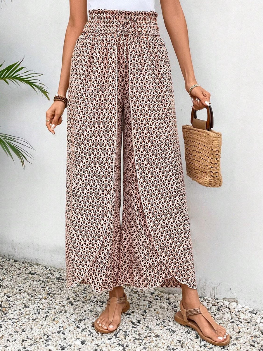 Palazzo pants with a geometric floral print in blush pink and black, featuring a wrap-front and wide legs.
