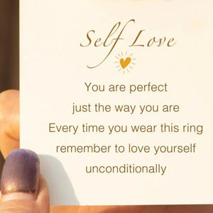 Gold two-tone heart outline ring detail on card with self-love message.