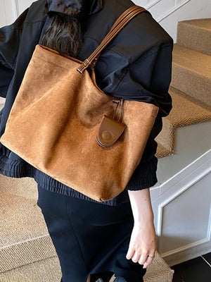 Large caramel brown suede tote bag with leather straps and a small leather tag detail.