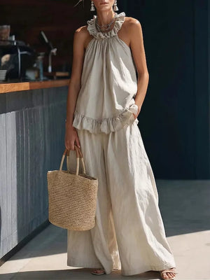 Apricot ruffled halter neck top and wide-leg pants set with a straw tote bag.