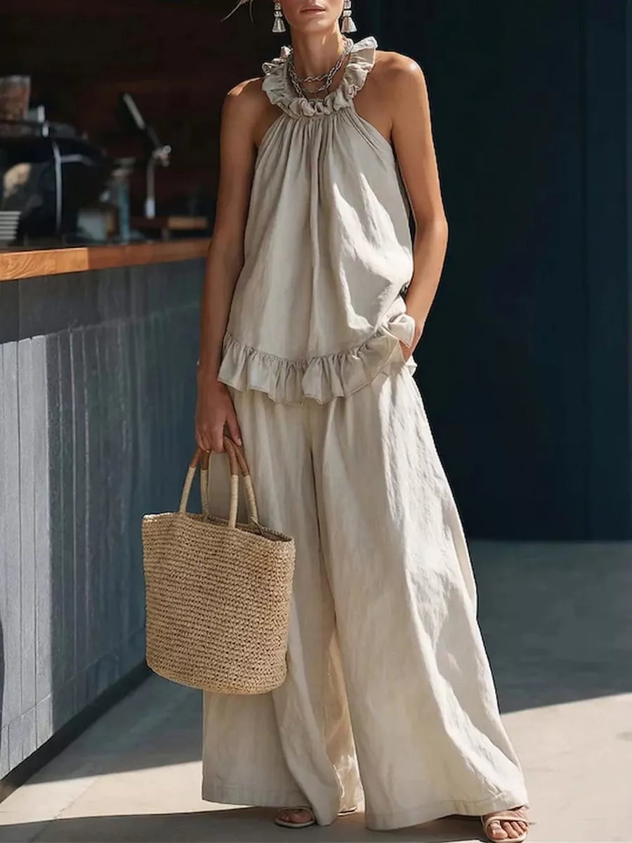 Apricot ruffled halter neck top and wide-leg pants set with a straw tote bag.