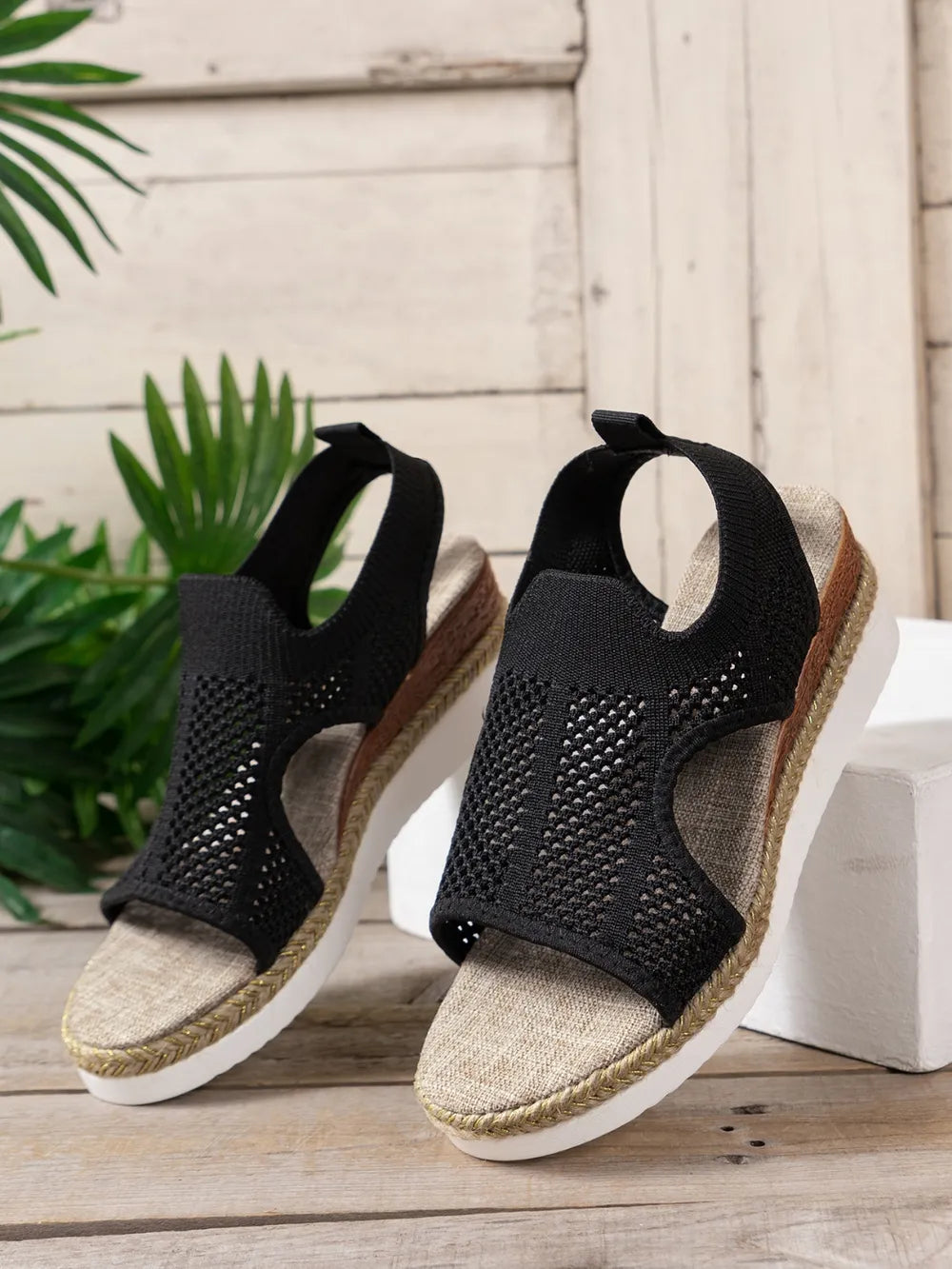 Black knit cutout espadrille wedge sandals with slingback strap and woven sole detail.