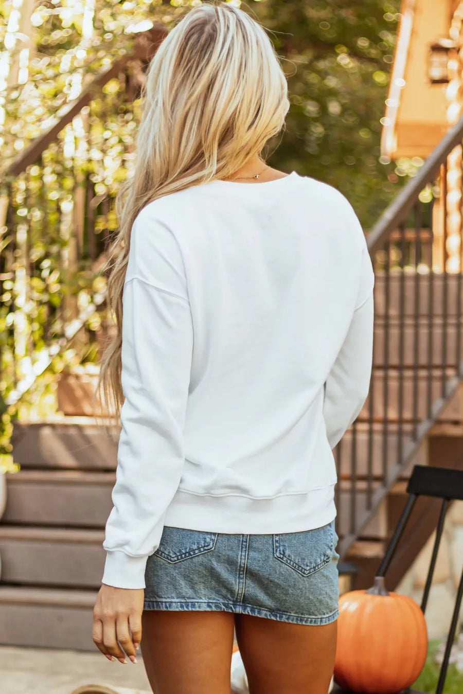 White crewneck sweatshirt with watercolor pumpkin graphic, casual long sleeves.