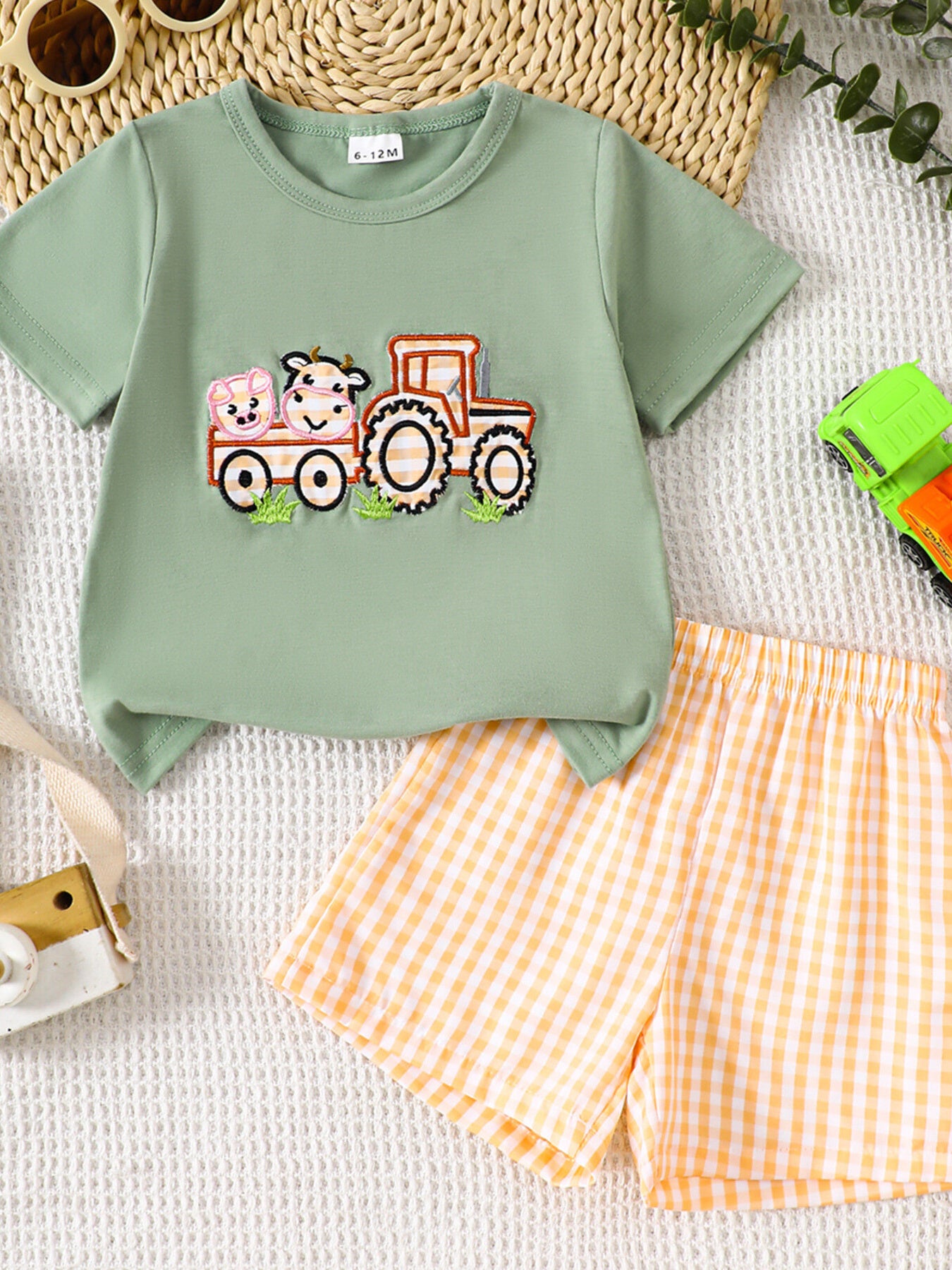 Light green baby tee with embroidered tractor and animals, paired with orange gingham shorts.