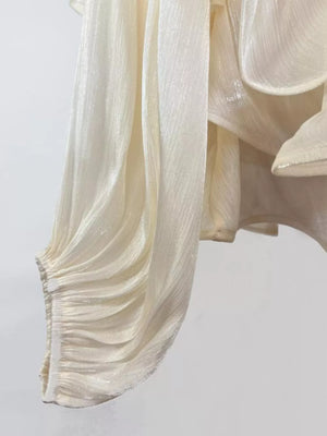 White ruffled mini dress with ruched sleeve detail and shimmering fabric.