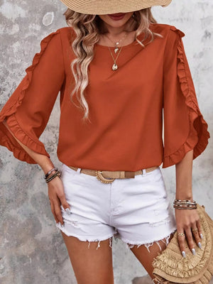 Orange ruffled sleeve blouse with button detail, styled with white shorts.