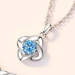 Delicate silver necklace with four-leaf clover charm and blue crystal.