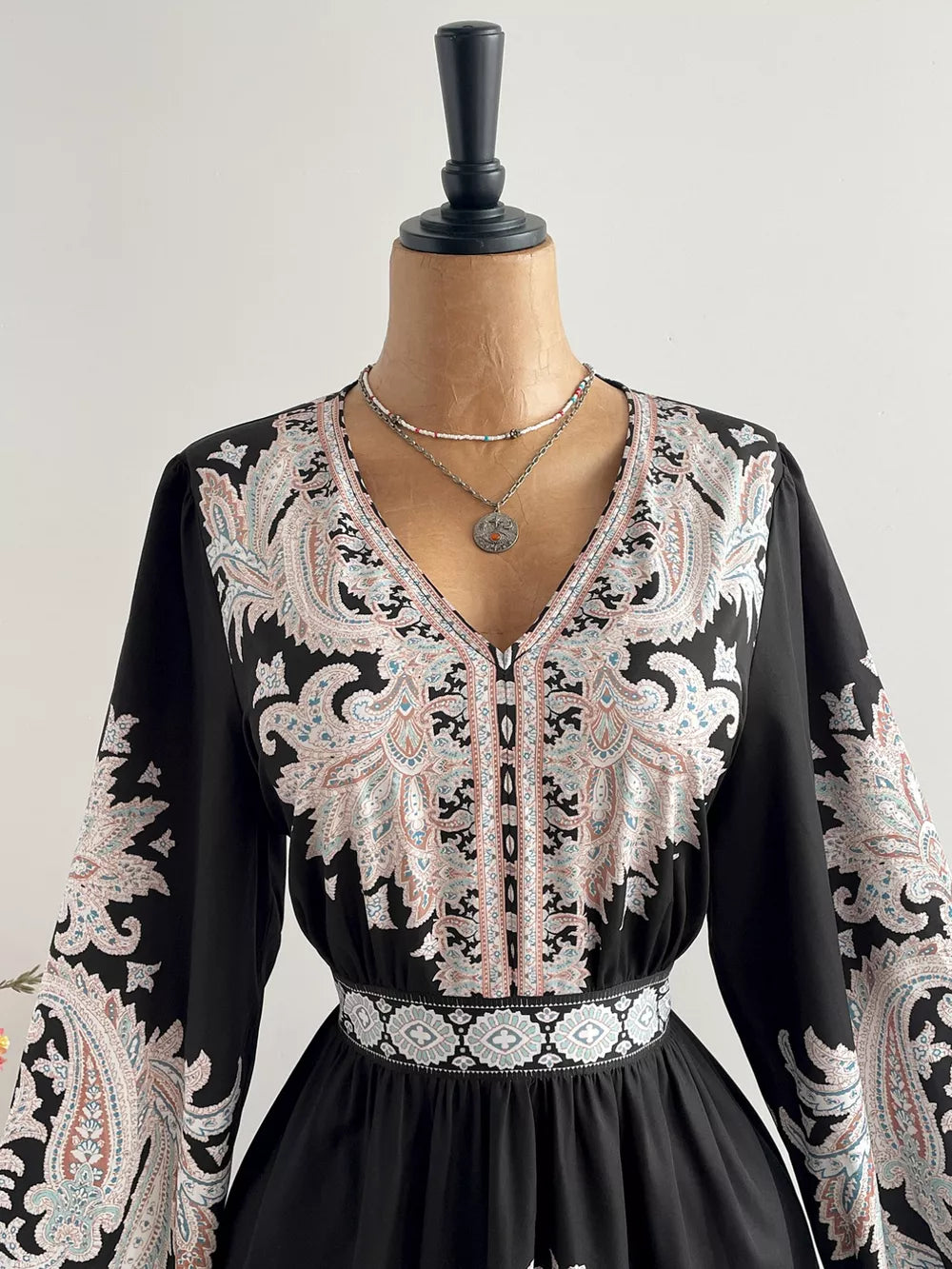 Black maxi dress with V-neck, balloon sleeves, and ornate paisley print.