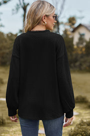 Black cable knit pullover sweater with textured pattern and long sleeves.