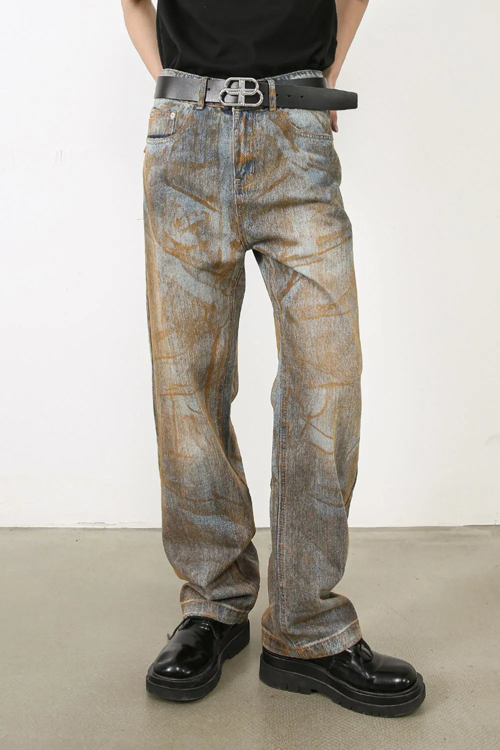 Relaxed fit acid wash denim jeans in medium blue with brown abstract pattern.
