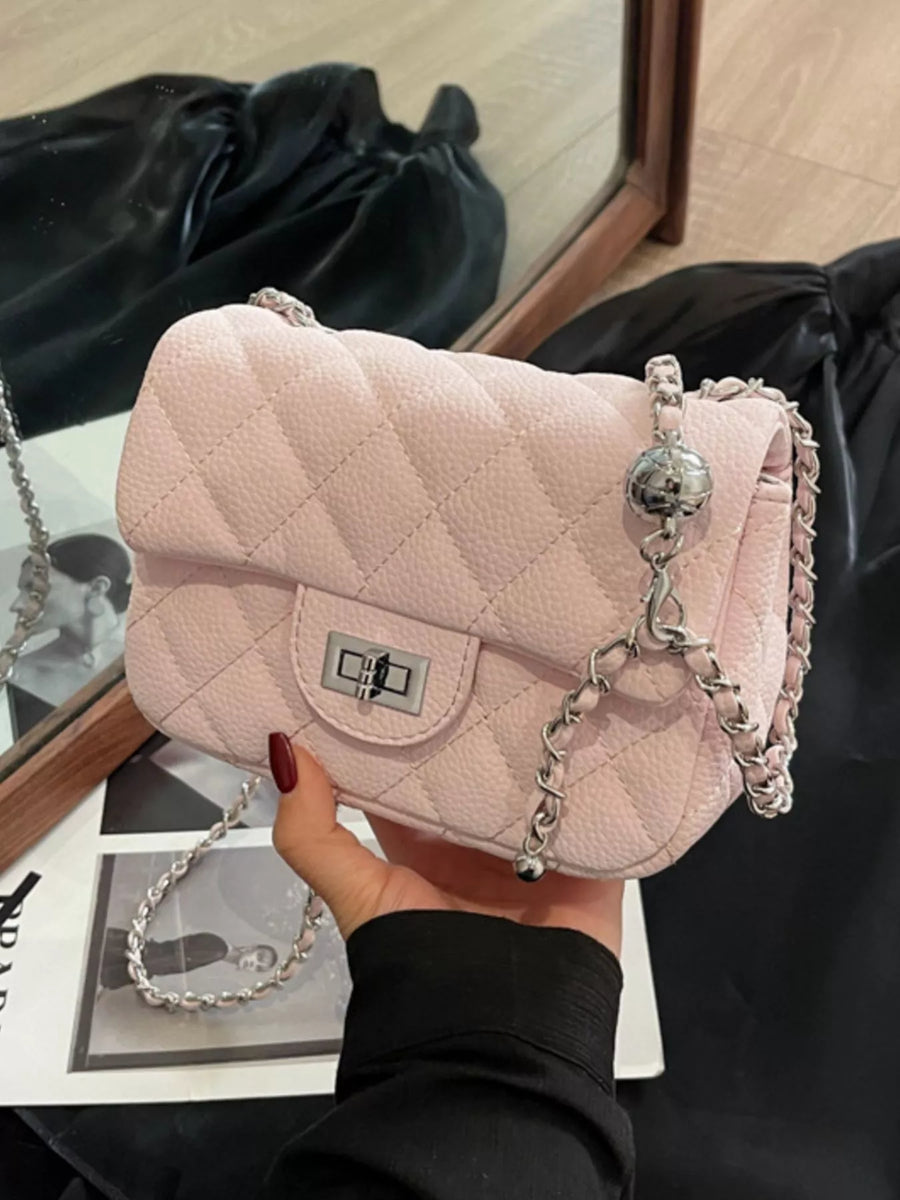 Pink quilted chain crossbody clutch bag with silver hardware and a decorative ball charm.