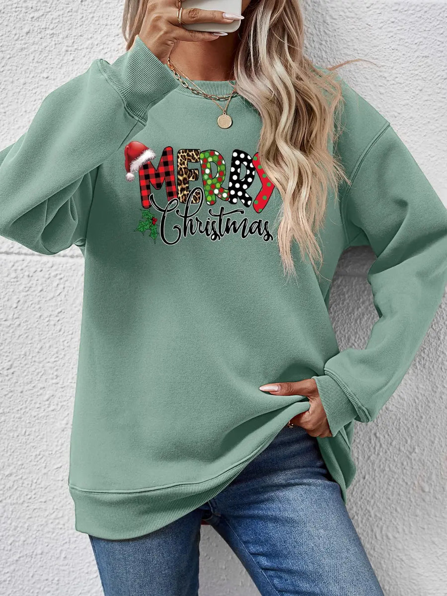 Sage green drop shoulder sweatshirt with "Merry Christmas" graphic in festive patterns.