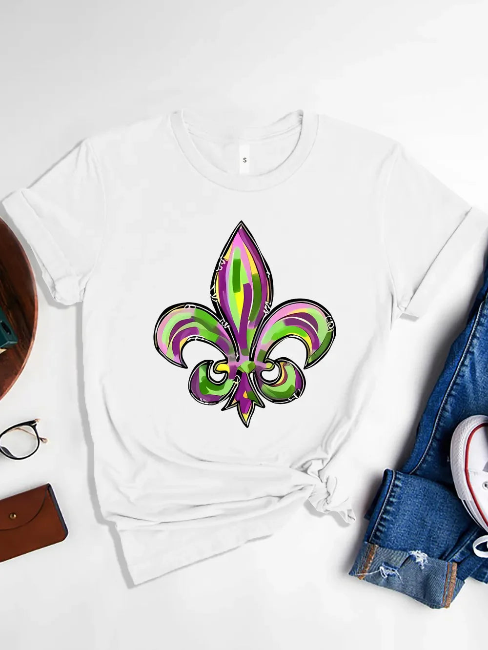 White t-shirt with a colorful Mardi Gras fleur-de-lis graphic print.