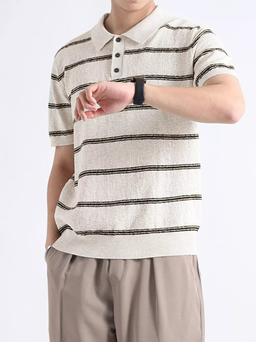 Striped knit polo shirt in off-white with black stripes, short sleeves, and button accents.