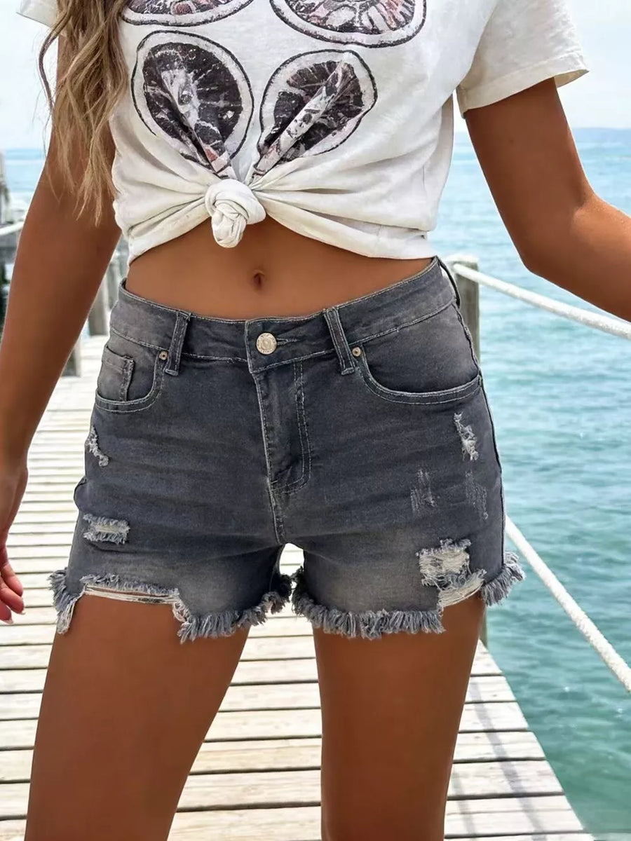 Gray distressed denim shorts with raw frayed hem and button fly.