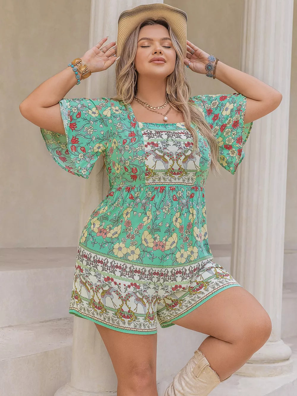 Plus-size green floral romper with square neck, flutter sleeves, and cinched waist.
