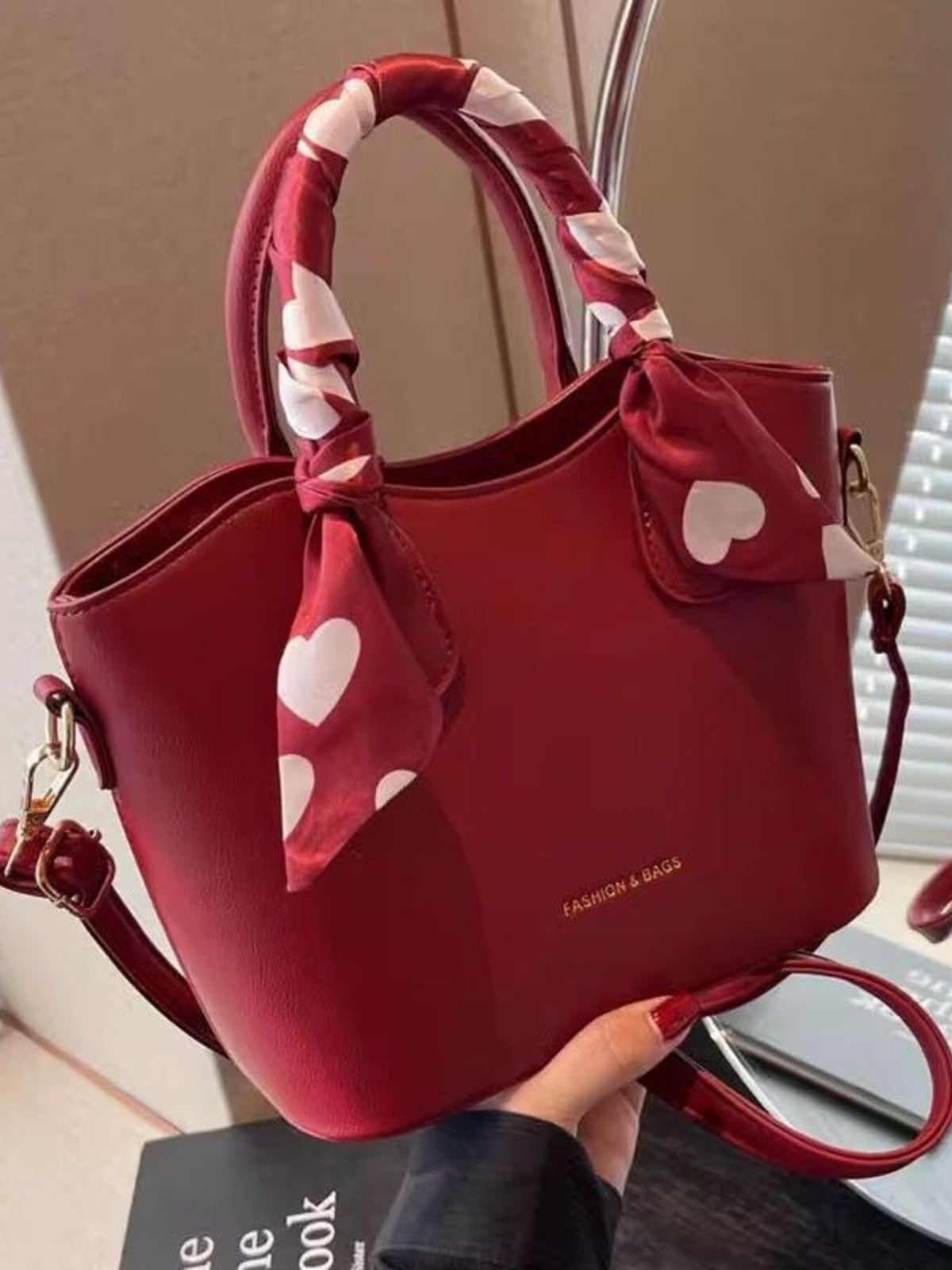 Red pu leather bucket bag with heart print scarf detail and gold hardware.