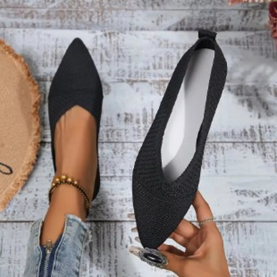 Black knit pointed toe flats with a low heel and elastic trim.