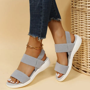 Sporty knit strap sandals in dark gray with white soles and a gold ankle bracelet.