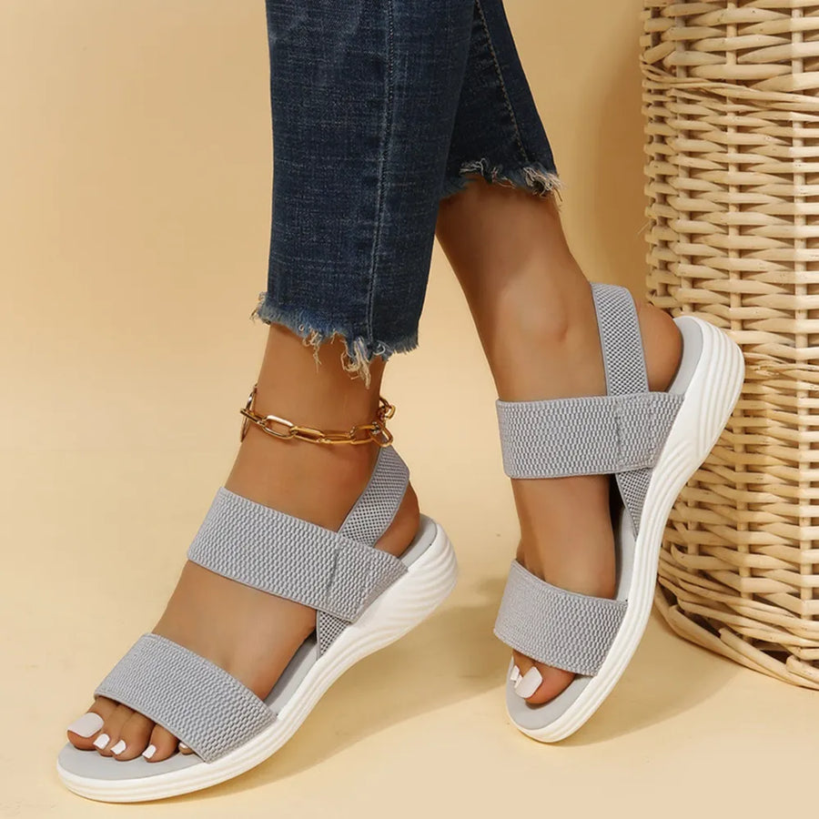 Sporty knit strap sandals in dark gray with white soles and a gold ankle bracelet.