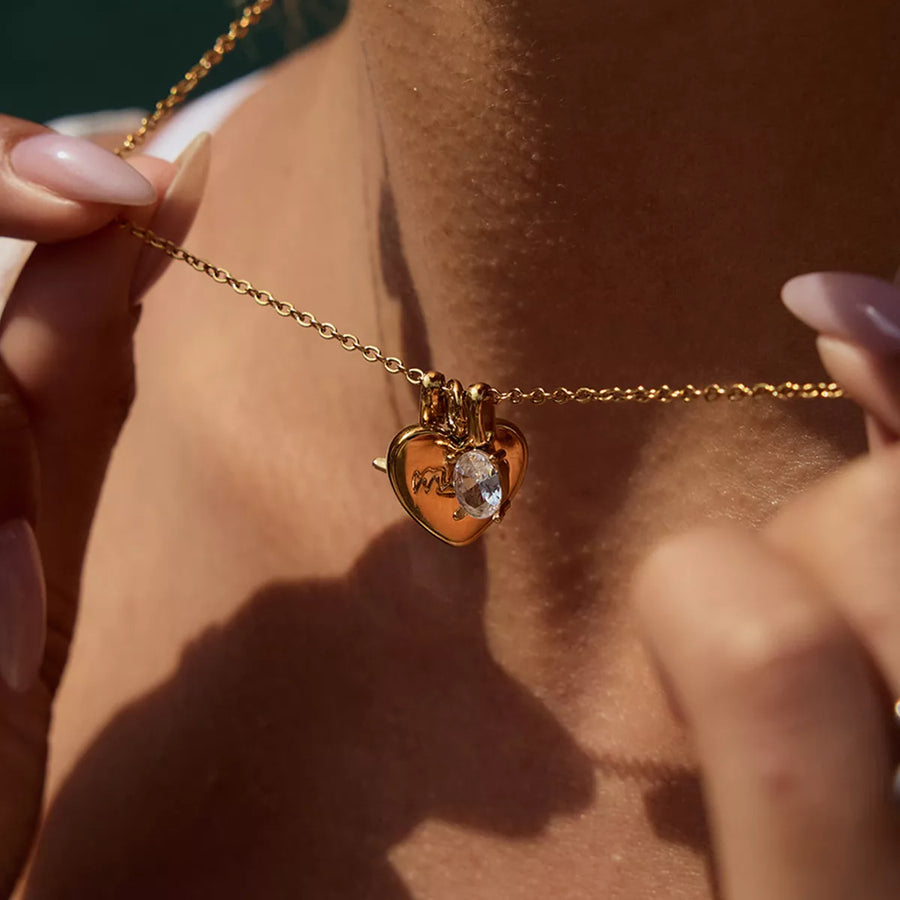 Gold heart charm necklace with crystal accent and engraved "Mom" detail.