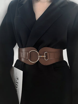 Brown cincher belt with sculpted silver buckle detail worn over a black blazer.