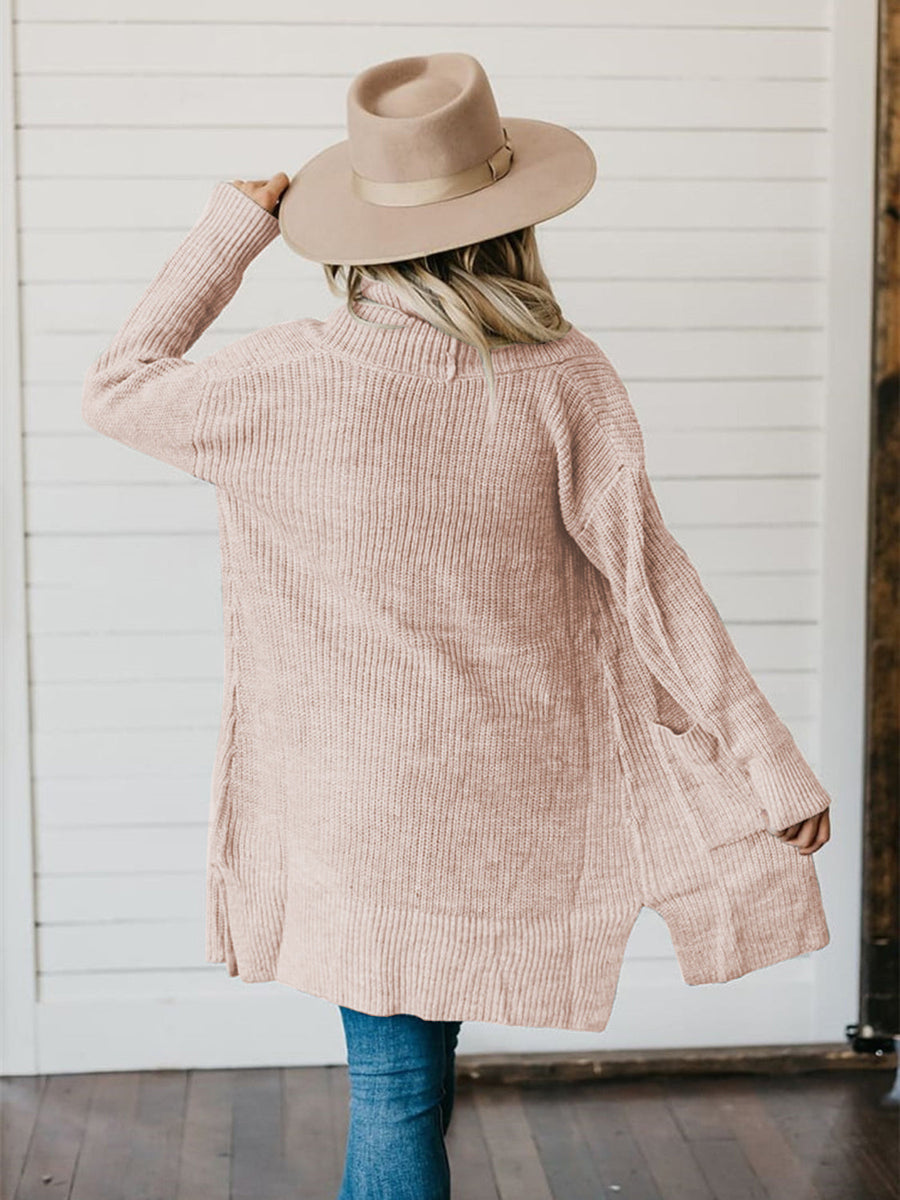 Apricot ribbed knit cardigan with pockets and side slits, worn by a woman in a hat.