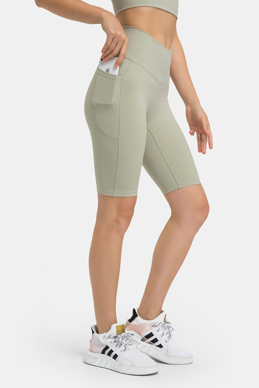 Sage V-waist biker shorts with pockets, showing a phone in the side pocket.