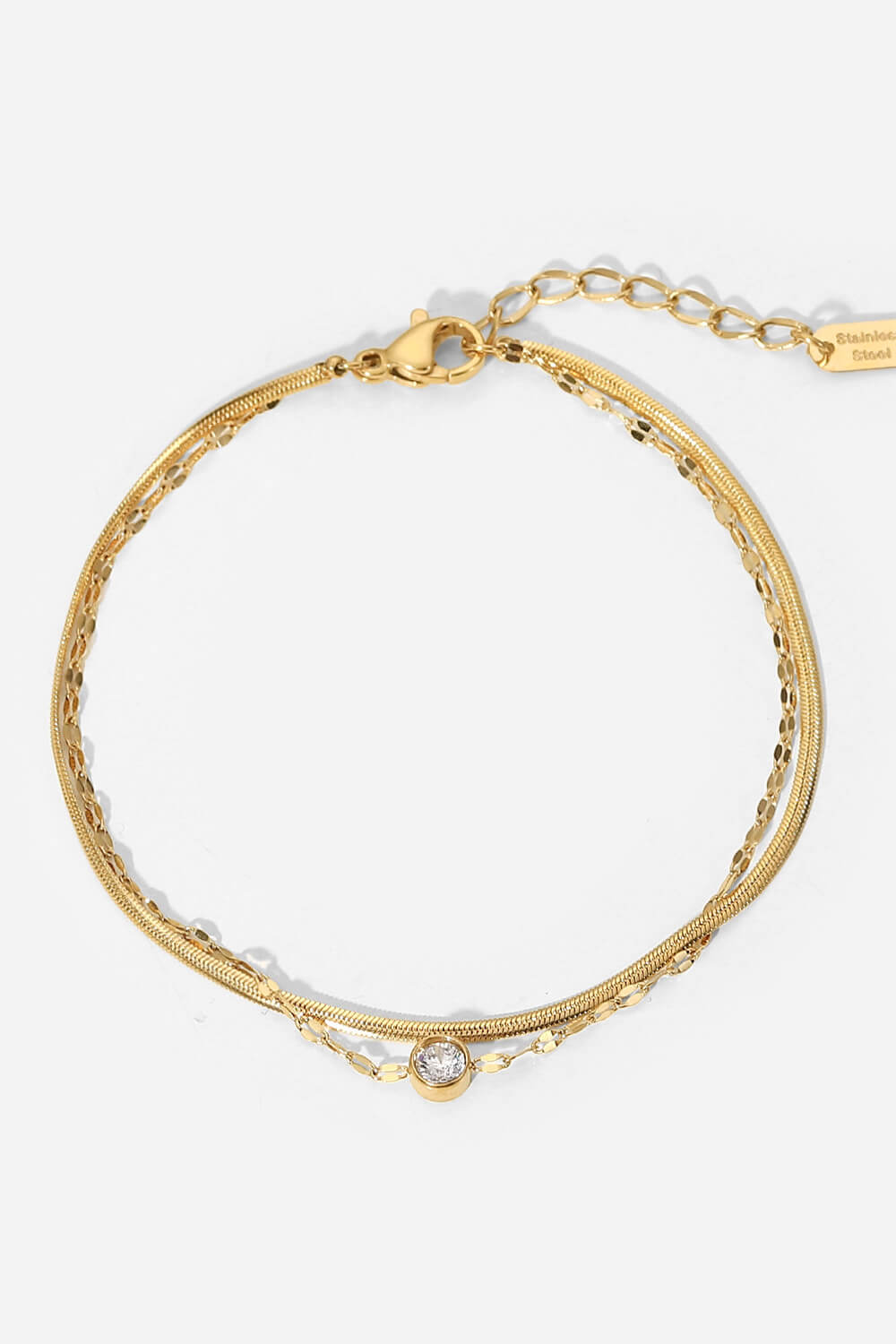 Gold double-strand pavé charm bracelet with a single clear stone accent.