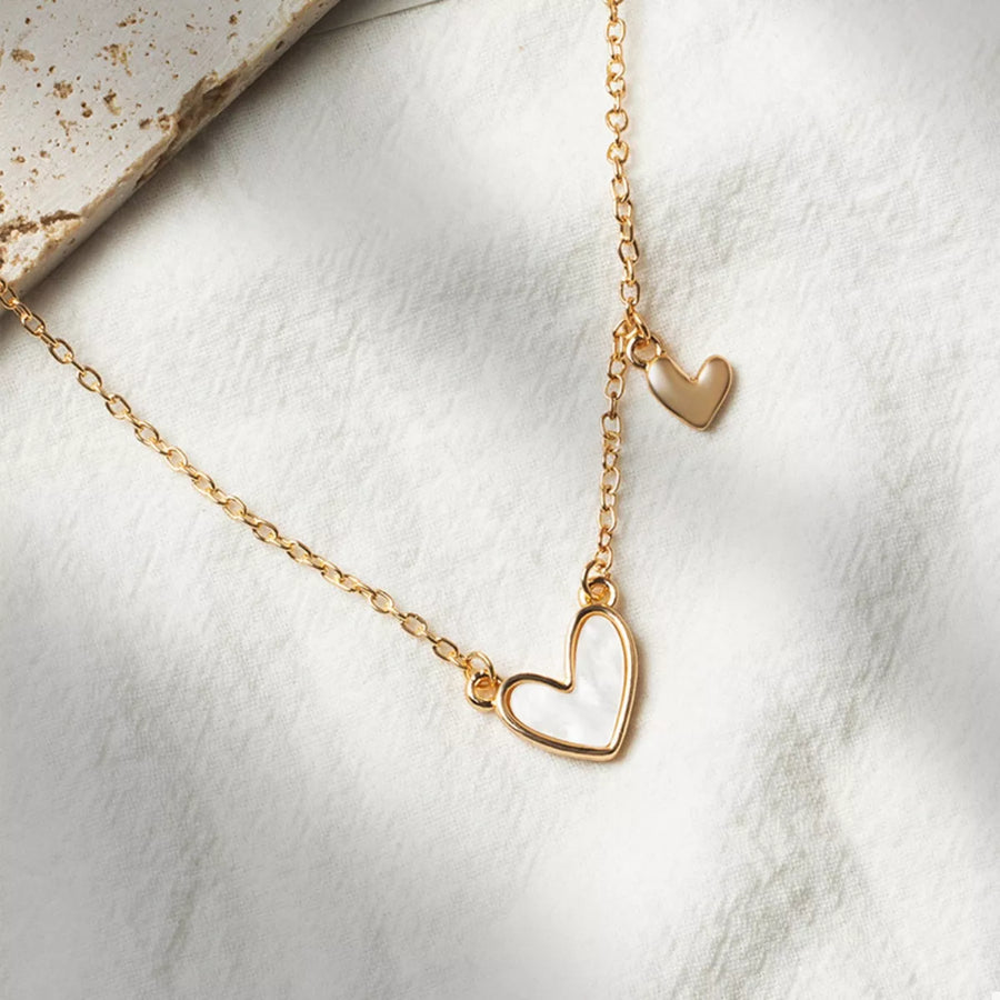 Gold necklace with white heart pendant and small gold heart charm