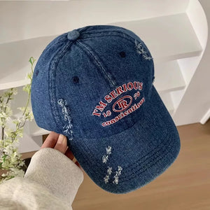 Denim baseball cap with distressed details and red embroidered text.