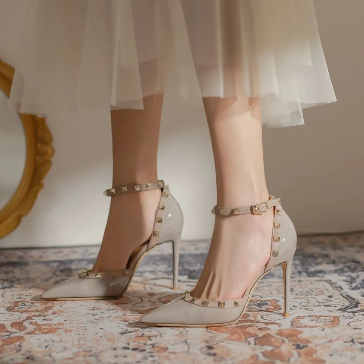 Apricot patent leather studded ankle strap pumps with pointed toe and stiletto heel.