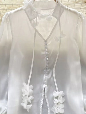 White sheer button-down shirt with delicate floral appliqué and ribbon ties.