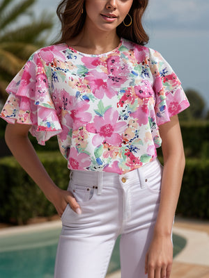 Watercolor floral blouse with tiered ruffle sleeves and a crew neck, styled with white jeans.