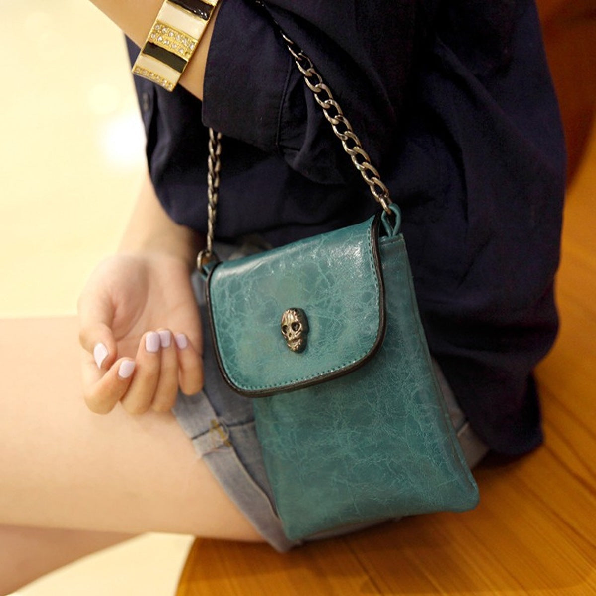 crossbody bag in teal featuring skull embellishment and boxy fit