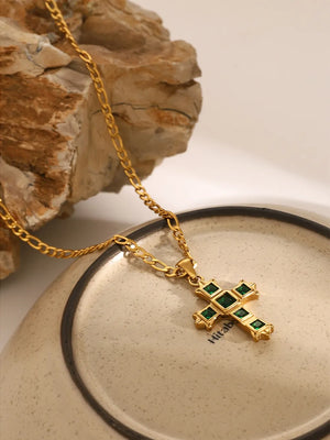 Gold cross pendant necklace with green zirconia stones on a figaro chain.