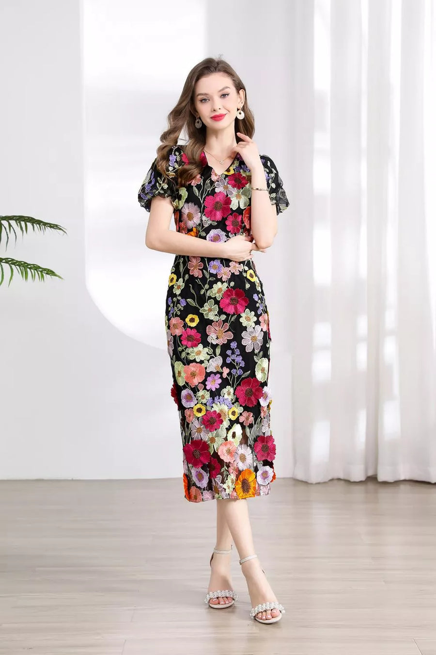 Black midi dress with colorful floral embroidery, V-neck, short puff sleeves, and a fitted silhouette.